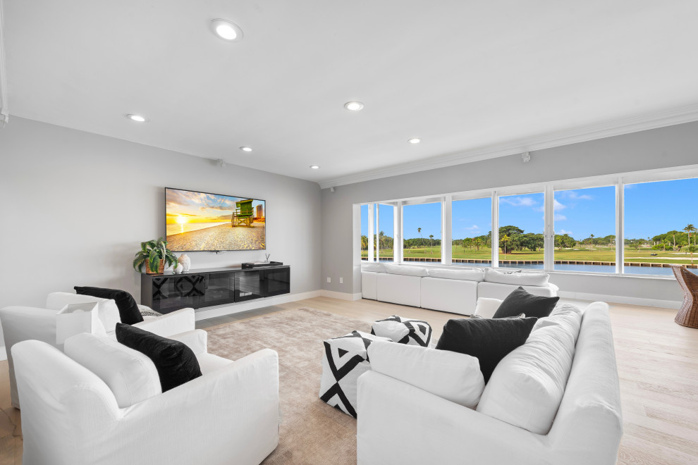Large modern formal open plan living room in Tampa with grey walls, light hardwood flooring, no fireplace, a wall mounted tv and brown floors.