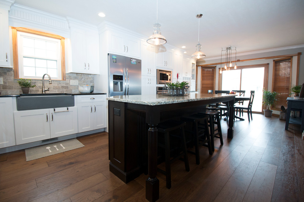Eat-in kitchen - large transitional l-shaped medium tone wood floor eat-in kitchen idea with an undermount sink, shaker cabinets, white cabinets, granite countertops, gray backsplash, stone tile backsplash, stainless steel appliances and an island