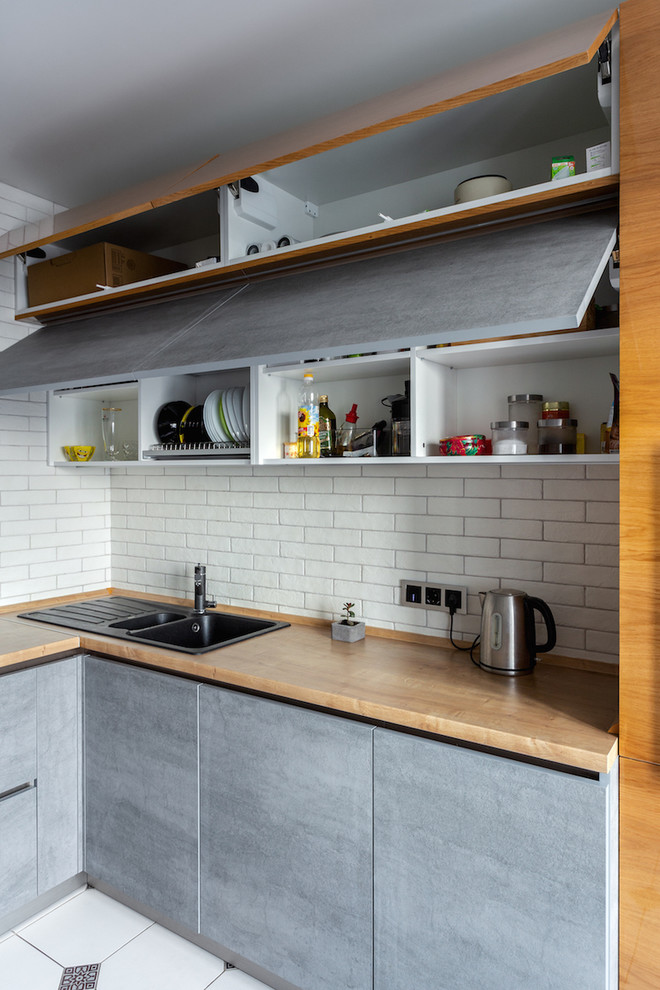 Photo of a mid-sized industrial l-shaped separate kitchen in Moscow with a drop-in sink, flat-panel cabinets, grey cabinets, laminate benchtops, brick splashback, coloured appliances, ceramic floors, no island and white floor.