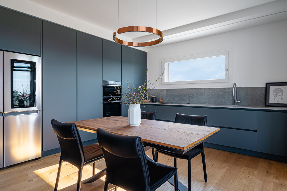 Design ideas for a large contemporary open plan kitchen in Other with a submerged sink, flat-panel cabinets, grey splashback, stainless steel appliances, light hardwood flooring, no island, grey worktops and green cabinets.