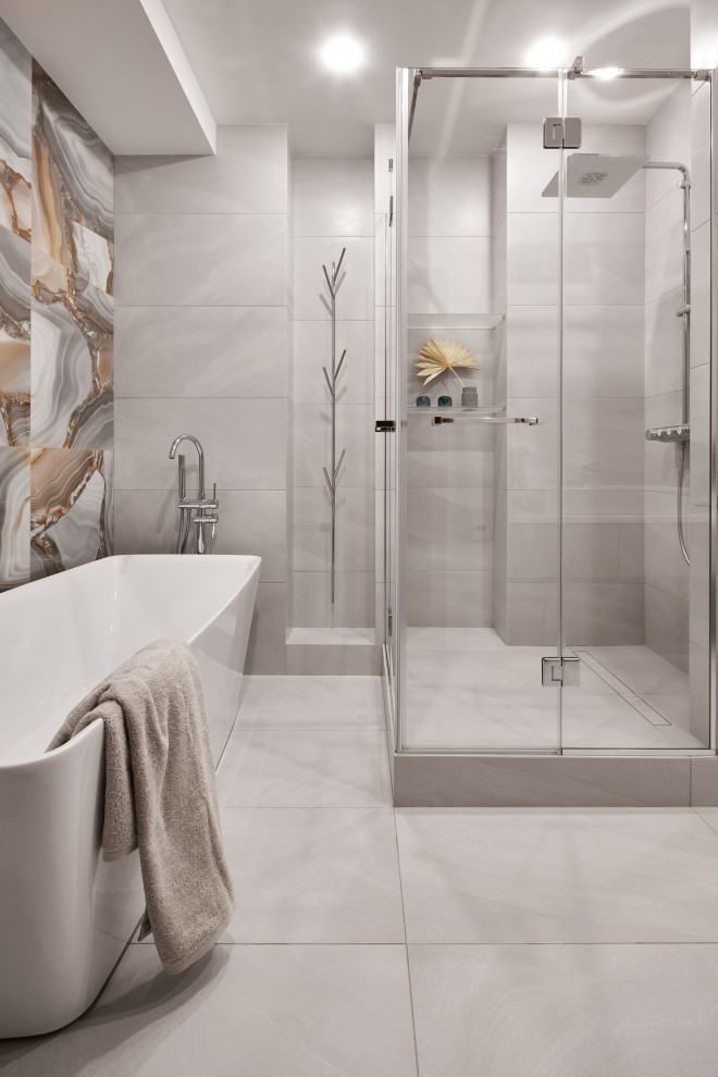 Large contemporary grey and white shower room bathroom in Saint Petersburg with flat-panel cabinets, grey cabinets, a freestanding bath, a corner shower, a wall mounted toilet, grey tiles, porcelain tiles, grey walls, porcelain flooring, a built-in sink, solid surface worktops, grey floors, a hinged door, a single sink and a floating vanity unit.