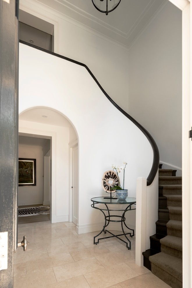 Photo of a large transitional foyer in Sydney with white walls, limestone floors and a single front door.