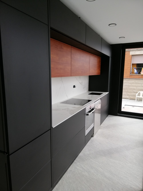 Modern galley kitchen with matte black and wood grain aluminum kitchen cabinets and a white countertop during installation