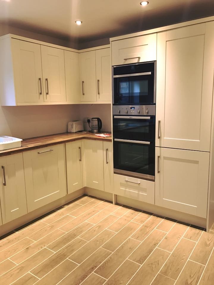 Mid-sized transitional u-shaped separate kitchen in West Midlands with an integrated sink, shaker cabinets, beige cabinets, laminate benchtops, beige splashback, glass sheet splashback, stainless steel appliances, ceramic floors, no island and beige floor.