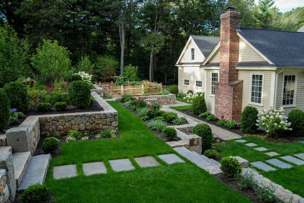 Design ideas for a mid-sized traditional backyard full sun garden in Boston with natural stone pavers and a retaining wall.