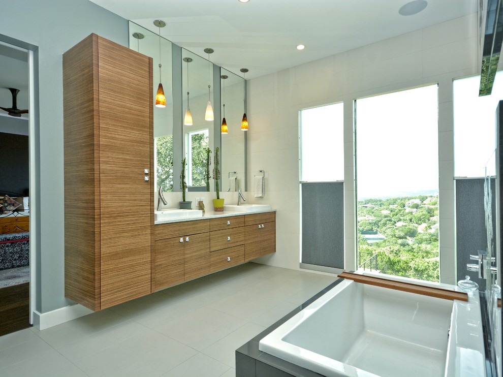 Photo of a large contemporary master bathroom in Austin with a drop-in sink, flat-panel cabinets, medium wood cabinets, a drop-in tub, white tile, grey walls, porcelain tile, porcelain floors, engineered quartz benchtops and beige floor.