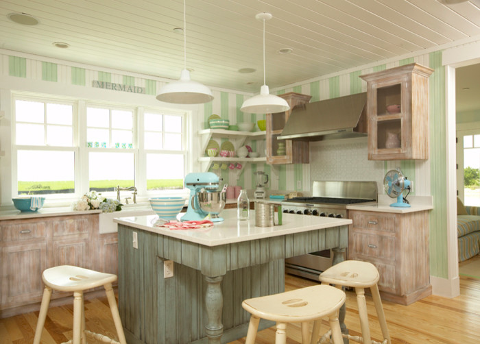 Coastal Living - Eat-in kitchen - mid-sized coastal u-shaped light wood floor and brown floor eat-in kitchen idea in Tampa with a farmhouse sink, flat-panel cabinets, beige backsplash, wood backsplash, stainless steel appliances, an island, distressed cabinets and beige countertops