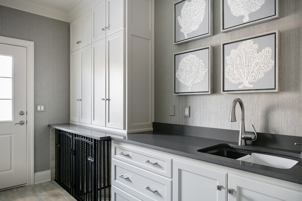 Photo of a large transitional galley utility room in Kansas City with an undermount sink, beaded inset cabinets, white cabinets, quartz benchtops, grey walls, porcelain floors, a side-by-side washer and dryer, grey floor and grey benchtop.