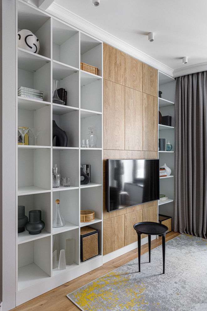 Ispirazione per un piccolo soggiorno minimal con libreria, pareti bianche, pavimento in legno massello medio e TV a parete