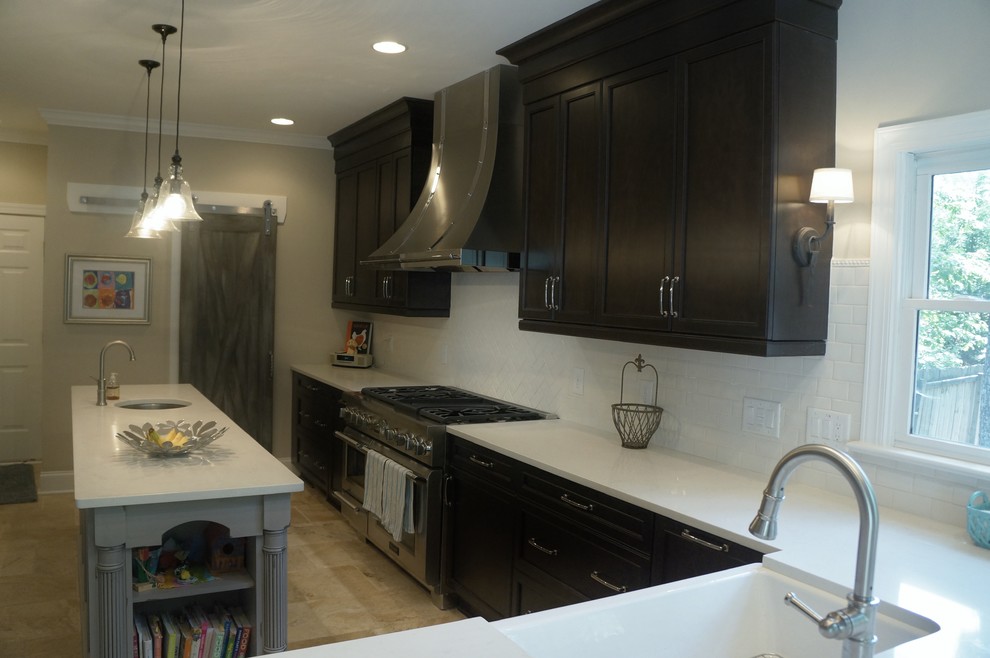 Example of a mid-sized transitional l-shaped travertine floor eat-in kitchen design in Raleigh with a farmhouse sink, flat-panel cabinets, dark wood cabinets, quartz countertops, white backsplash, ceramic backsplash, stainless steel appliances and an island