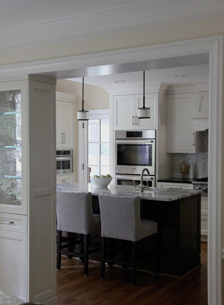 Example of a large transitional u-shaped medium tone wood floor eat-in kitchen design in DC Metro with a farmhouse sink, recessed-panel cabinets, white cabinets, quartzite countertops, white backsplash, mosaic tile backsplash, stainless steel appliances and an island