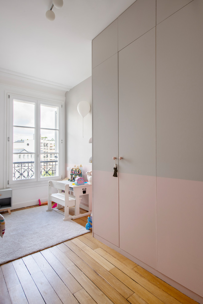 Foto di una cameretta per bambini da 4 a 10 anni design di medie dimensioni con pareti multicolore, parquet chiaro e pavimento beige