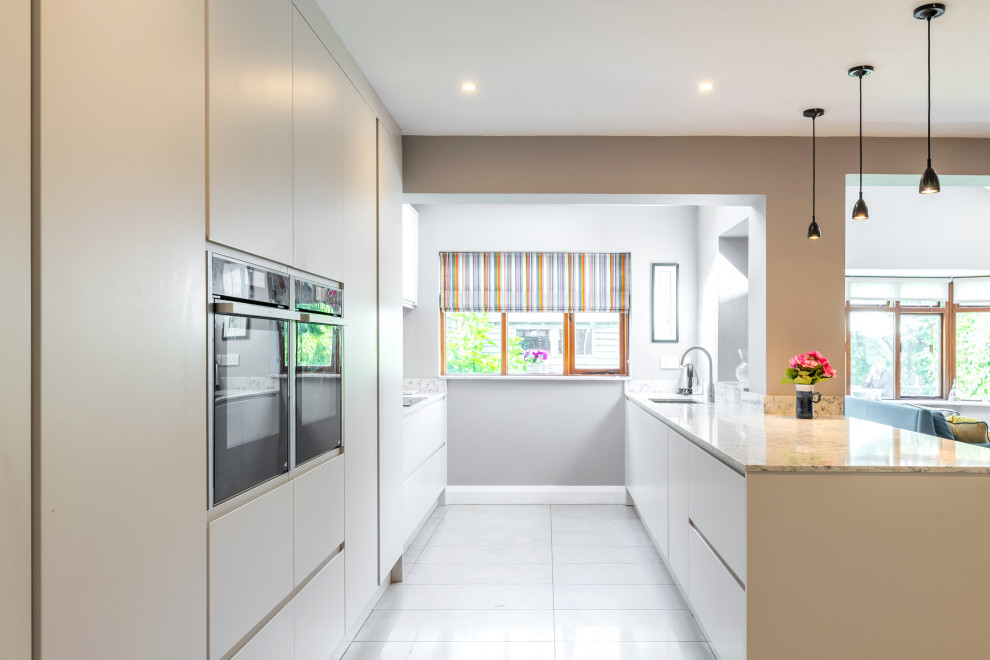 Design ideas for a mid-sized contemporary galley open plan kitchen in Dublin with an integrated sink, flat-panel cabinets, grey cabinets, quartzite benchtops, stainless steel appliances, porcelain floors, a peninsula, grey floor, blue splashback, engineered quartz splashback and blue benchtop.