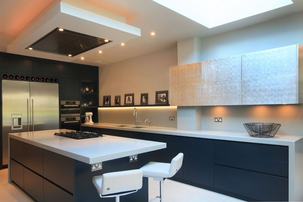Inspiration for a mid-sized contemporary l-shaped open plan kitchen in London with flat-panel cabinets, blue cabinets, quartzite benchtops, grey splashback, glass sheet splashback, stainless steel appliances, ceramic floors, a peninsula and an undermount sink.
