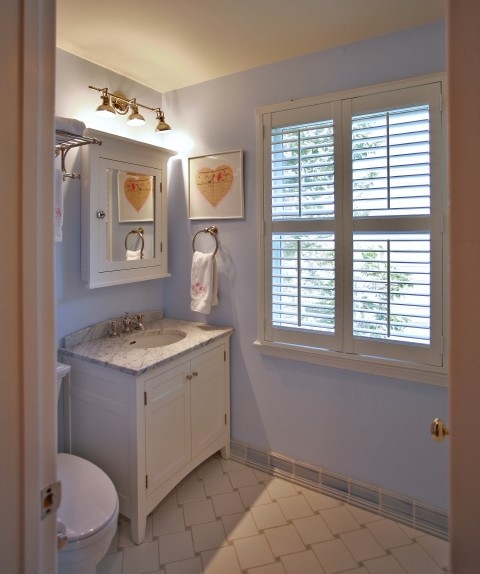 Photo of a mid-sized traditional 3/4 bathroom in DC Metro with shaker cabinets, white cabinets, a one-piece toilet, blue walls, ceramic floors, an undermount sink, marble benchtops, an alcove shower, blue tile, white tile and porcelain tile.