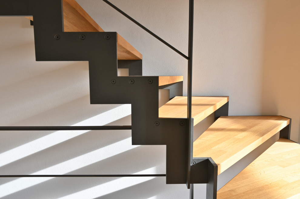 This is an example of a medium sized urban wood curved metal railing staircase in Munich with open risers.