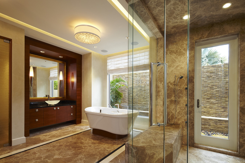Inspiration for a large contemporary master bathroom in Miami with a freestanding tub, a vessel sink, dark wood cabinets, a curbless shower, a one-piece toilet, brown tile, beige walls, marble floors, granite benchtops, flat-panel cabinets and marble.