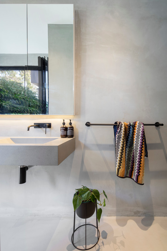 Design ideas for a mid-sized contemporary master bathroom in Melbourne with a freestanding tub, an open shower, a wall-mount toilet, concrete floors, an integrated sink and marble benchtops.