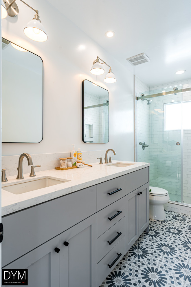 Example of a large classic master white tile and subway tile ceramic tile, multicolored floor, wallpaper ceiling, wallpaper and double-sink bathroom design in Los Angeles with a one-piece toilet, white walls, a drop-in sink, flat-panel cabinets, gray cabinets, marble countertops, white countertops and a built-in vanity