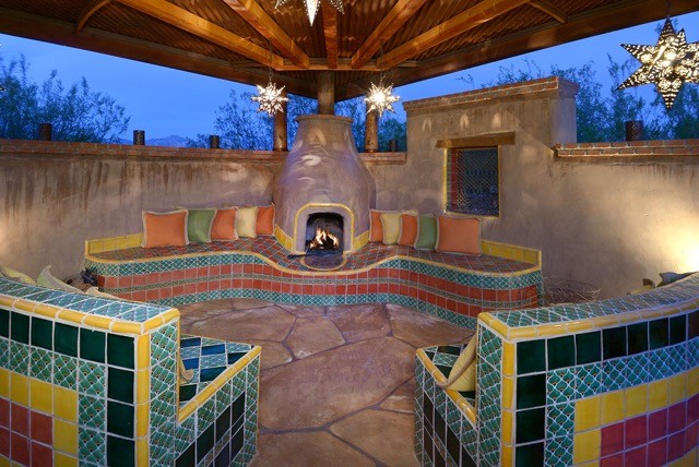 Photo of a large eclectic courtyard patio in Phoenix with a fire feature, concrete pavers and an awning.