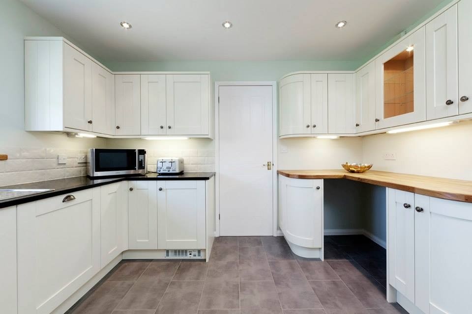 Design ideas for a large contemporary u-shaped separate kitchen in Essex with a double-bowl sink, beige cabinets, quartzite benchtops, beige splashback, ceramic splashback, black appliances, porcelain floors and with island.
