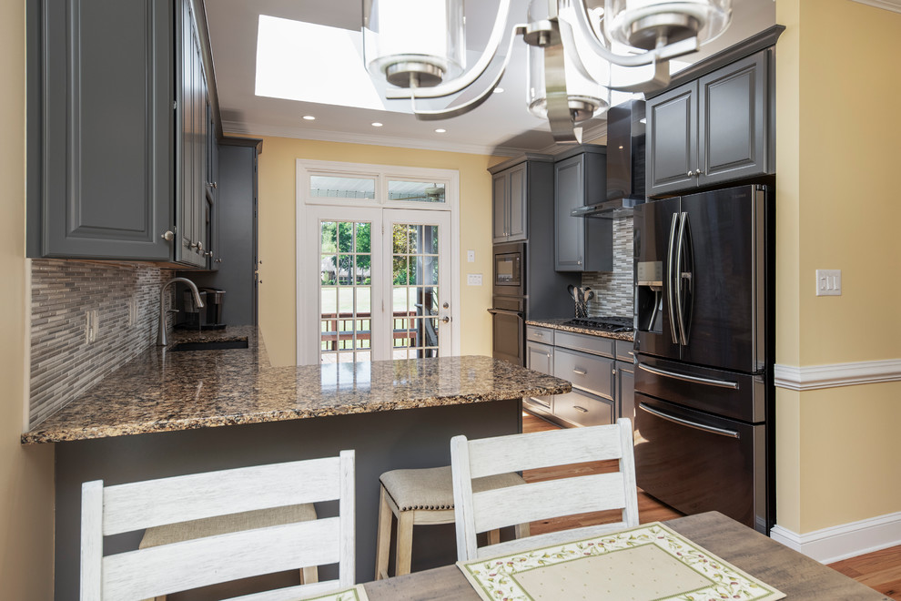 Inspiration for a transitional kitchen remodel with raised-panel cabinets, gray cabinets, granite countertops, black appliances, a peninsula and multicolored countertops