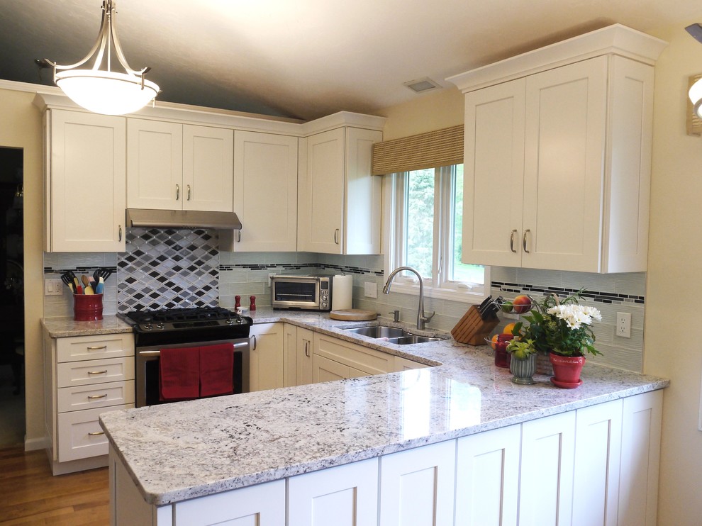 Inspiration for a mid-sized transitional u-shaped eat-in kitchen in Grand Rapids with shaker cabinets, white cabinets, granite benchtops, multi-coloured splashback, glass tile splashback, stainless steel appliances, medium hardwood floors, a peninsula and a double-bowl sink.