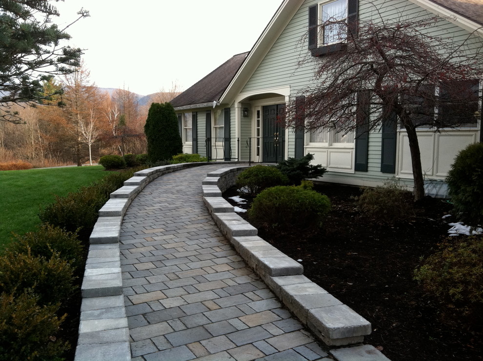Large transitional garden in Boston with concrete pavers and a retaining wall.