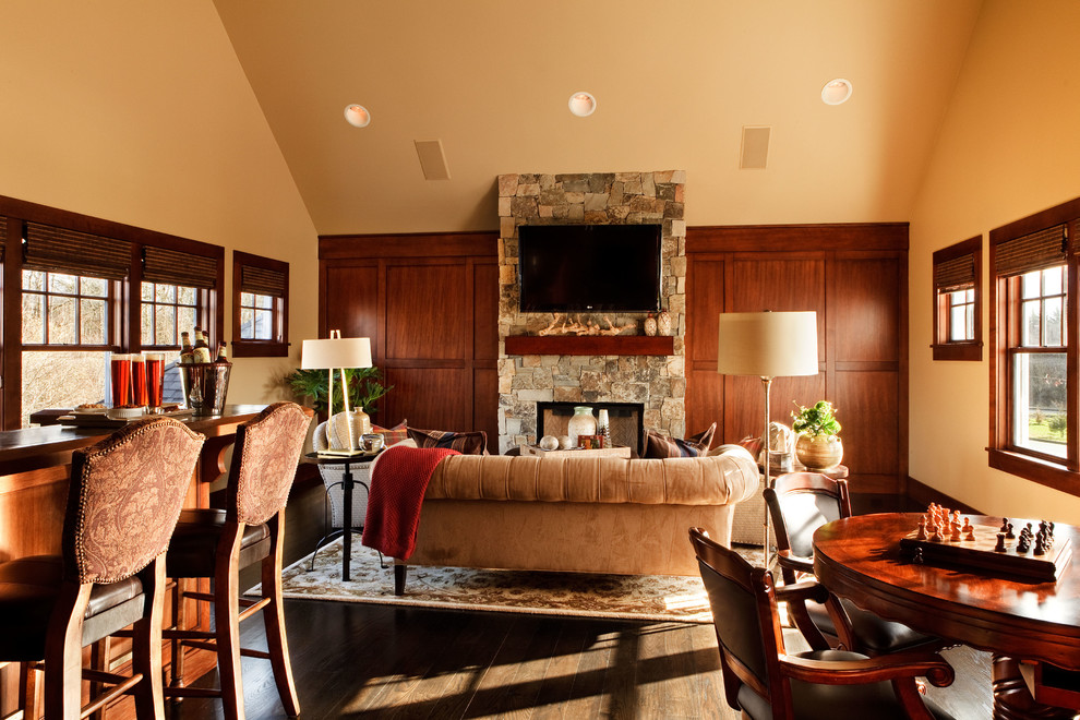 Photo of a large traditional enclosed family room in Portland with a home bar, dark hardwood floors, a standard fireplace, a stone fireplace surround and a wall-mounted tv.