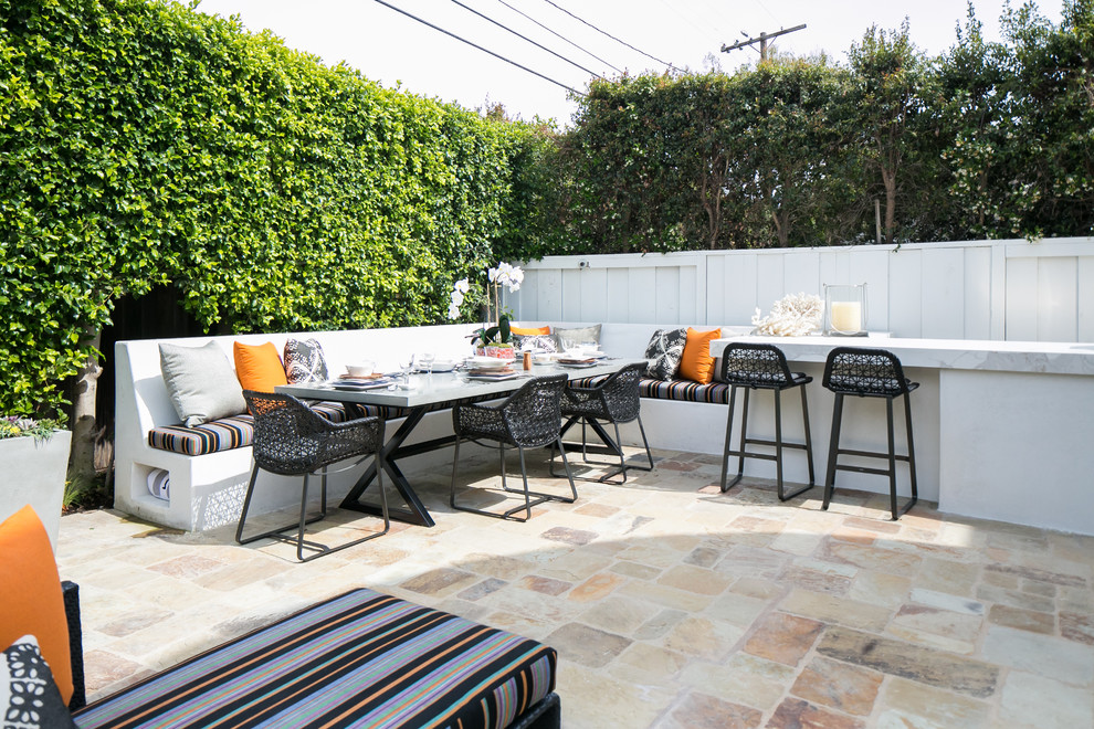 Example of a transitional backyard stone patio design in Orange County with no cover