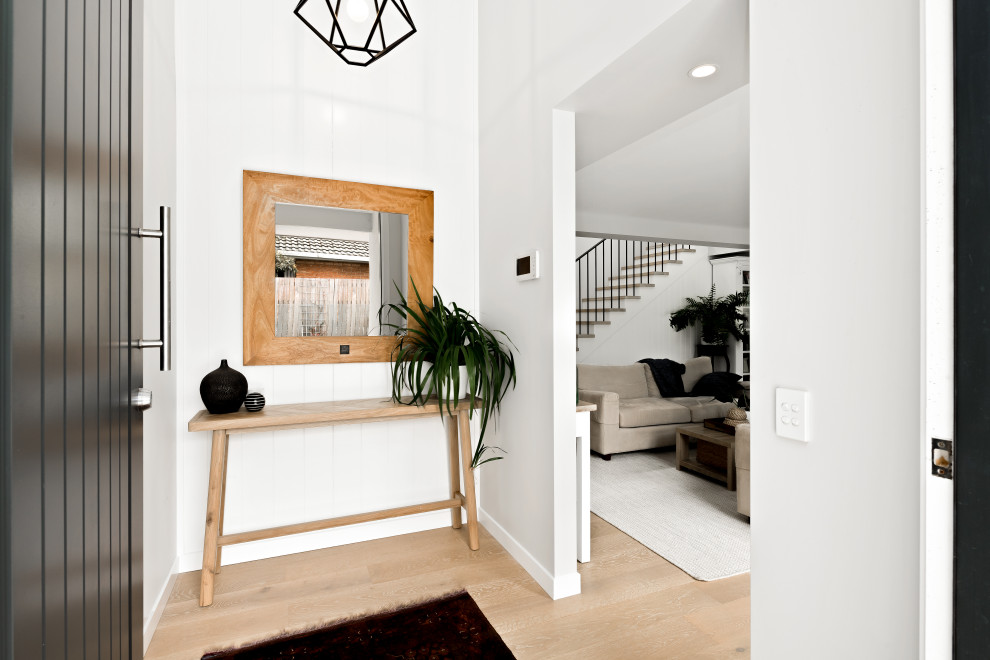 Small beach style foyer in Sunshine Coast with white walls, light hardwood floors, a pivot front door, a black front door, vaulted and panelled walls.