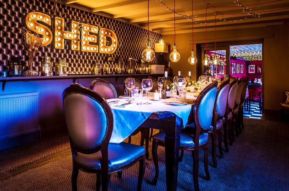 This is an example of a medium sized urban dining room in London with grey walls, banquette seating, vinyl flooring, wallpapered walls and feature lighting.