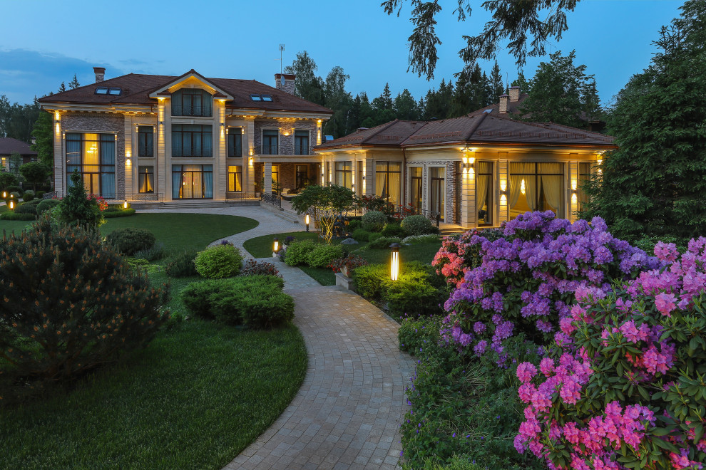 Immagine della villa grande multicolore classica a tre piani con rivestimento in pietra, tetto a padiglione, copertura in tegole, tetto marrone e pannelli sovrapposti