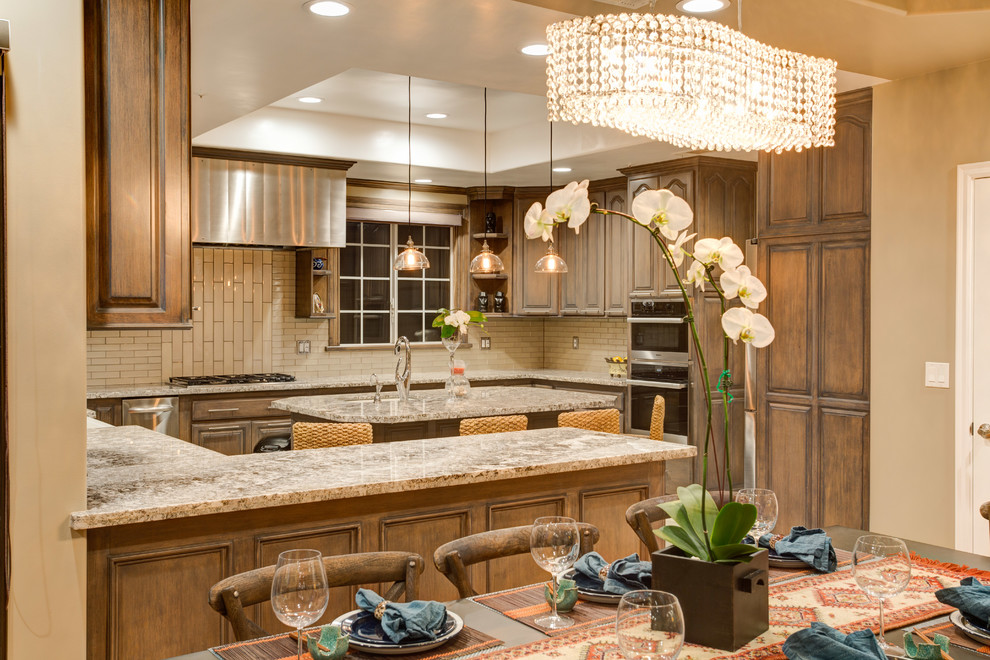 Inspiration for a huge transitional u-shaped porcelain tile open concept kitchen remodel in Los Angeles with a farmhouse sink, raised-panel cabinets, light wood cabinets, granite countertops, gray backsplash, glass tile backsplash, stainless steel appliances and an island