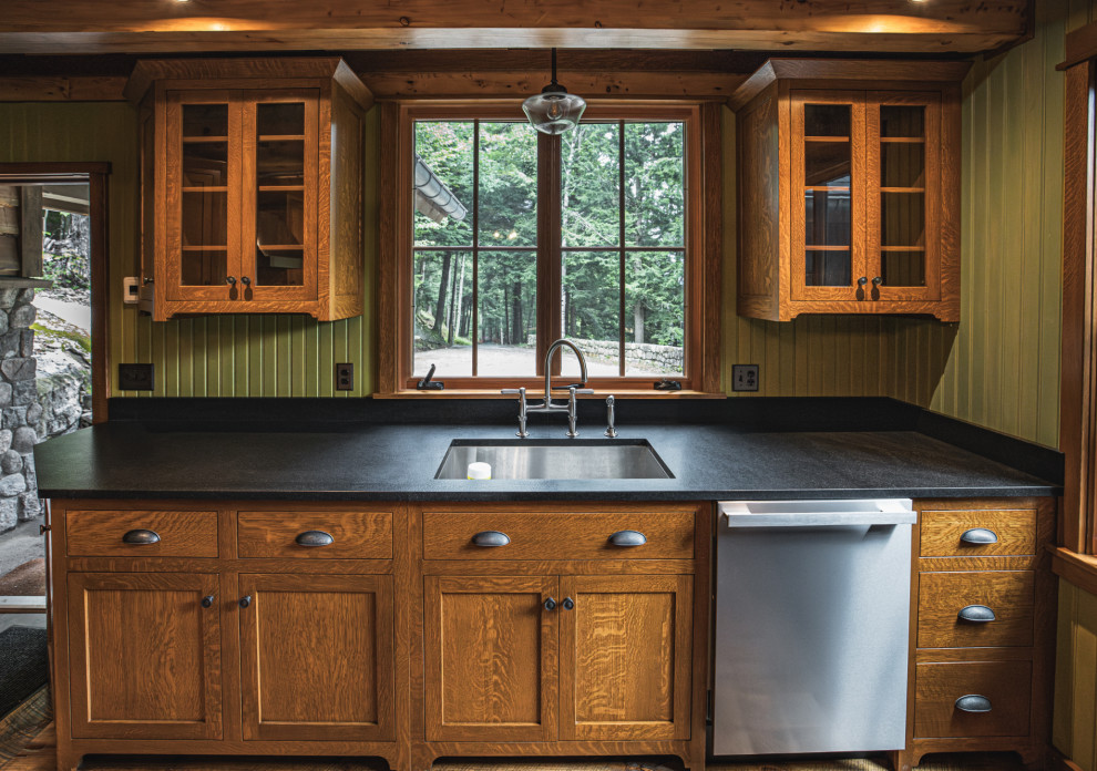Kitchen - rustic medium tone wood floor and exposed beam kitchen idea with an undermount sink, shaker cabinets, granite countertops, black backsplash, granite backsplash, stainless steel appliances, an island and black countertops