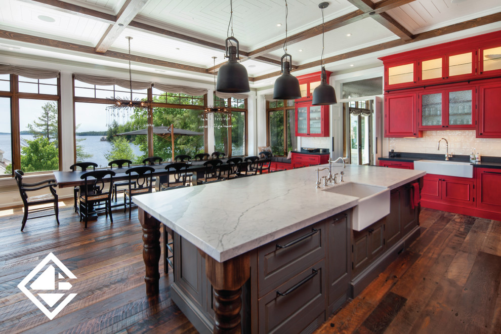 Inspiration for a huge rustic l-shaped medium tone wood floor eat-in kitchen remodel with a farmhouse sink, raised-panel cabinets, red cabinets, granite countertops, white backsplash, stainless steel appliances and an island