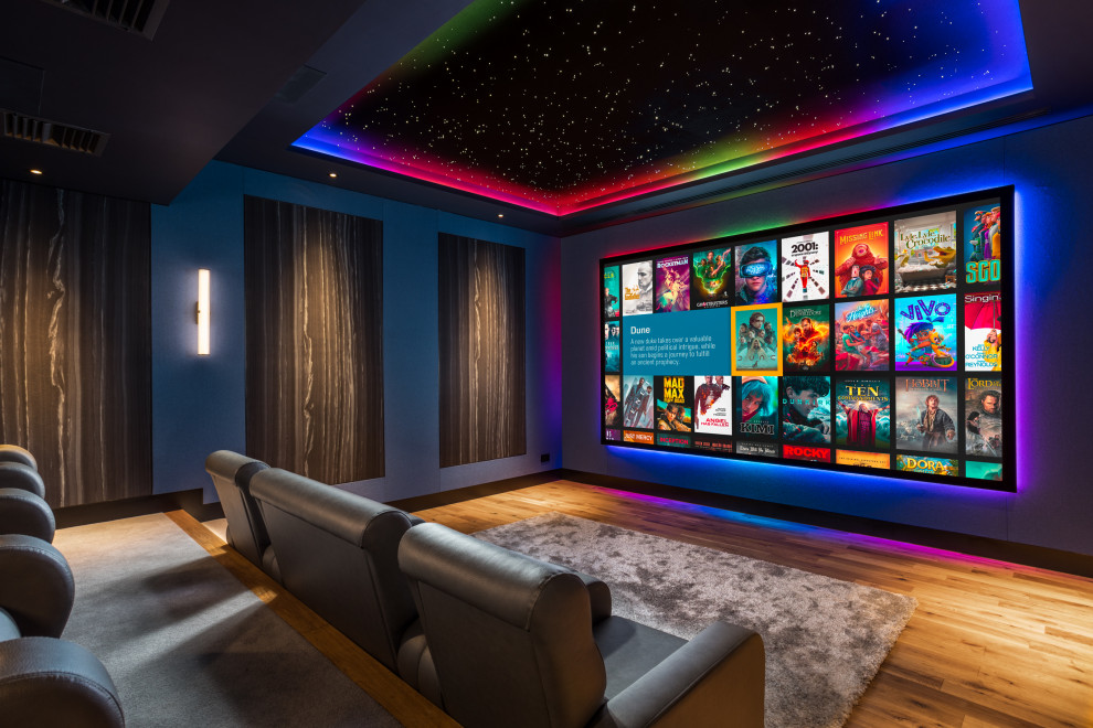 Modelo de cine en casa cerrado actual grande con paredes azules, suelo de madera clara y pantalla de proyección