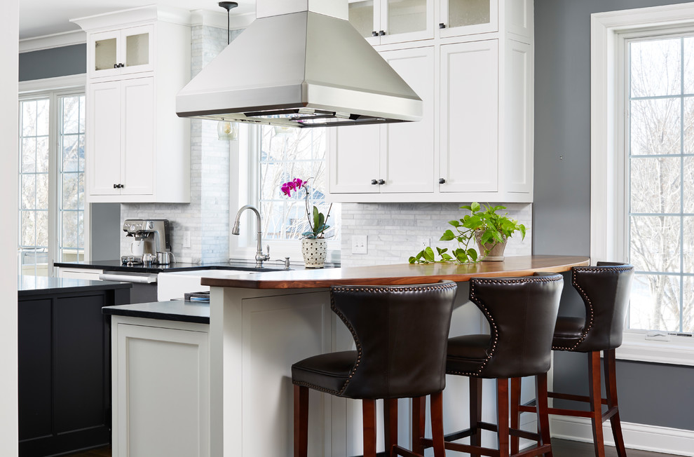Design ideas for a transitional kitchen in Minneapolis with a farmhouse sink, shaker cabinets, white cabinets, grey splashback, a peninsula and black benchtop.