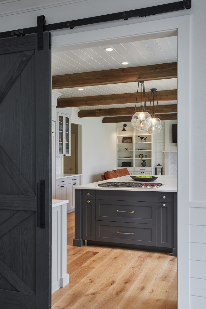 Mid-sized country kitchen/dining combo in Portland with white walls, light hardwood floors, exposed beam and planked wall panelling.