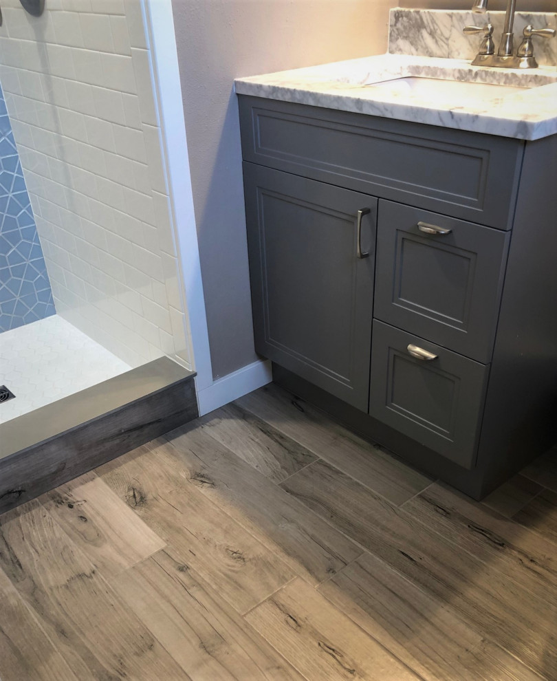 This is an example of a small contemporary 3/4 bathroom in Other with recessed-panel cabinets, grey cabinets, an alcove shower, white tile, subway tile, grey walls, vinyl floors, an undermount sink, granite benchtops, brown floor, a shower curtain, multi-coloured benchtops, a niche and a single vanity.