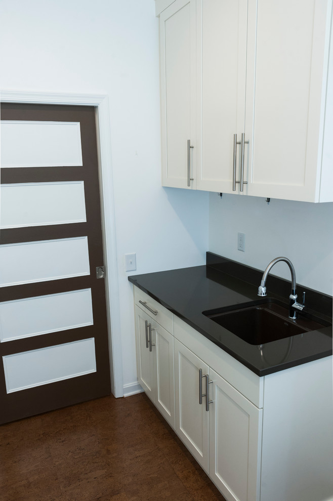 Photo of a laundry room in Philadelphia with white cabinets, cork floors, brown floor and recessed-panel cabinets.
