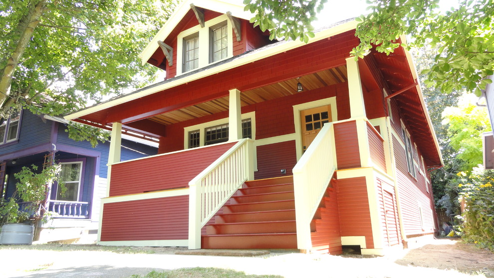 This is an example of a mid-sized arts and crafts two-storey red house exterior in Portland with wood siding, a gable roof and a shingle roof.