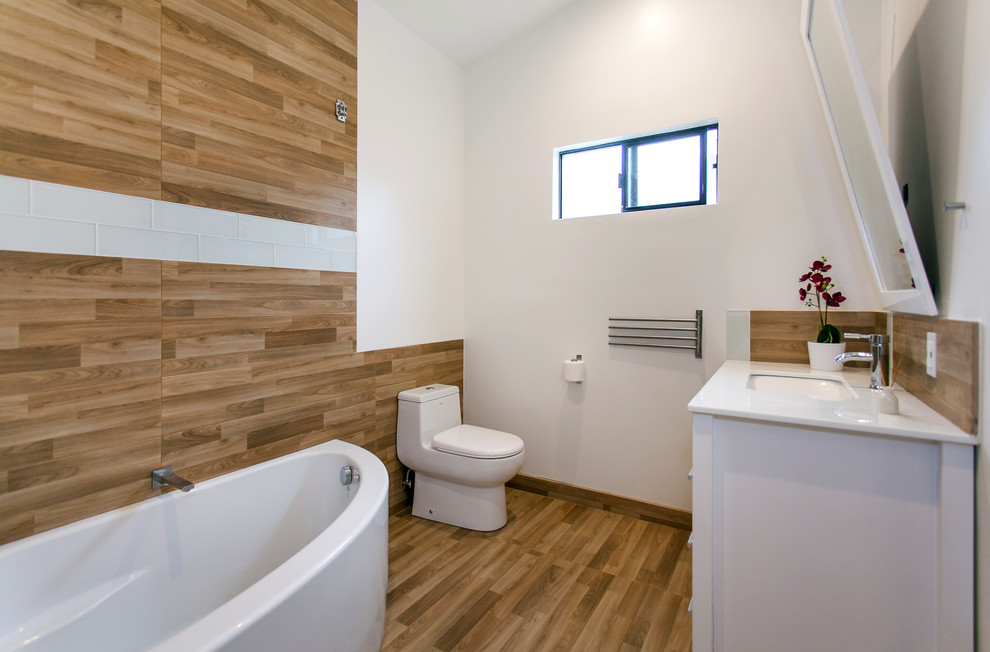 This is an example of a mid-sized modern 3/4 bathroom in Los Angeles with flat-panel cabinets, white cabinets, an alcove tub, a one-piece toilet, brown tile, porcelain tile, white walls, porcelain floors, an undermount sink, engineered quartz benchtops and brown floor.