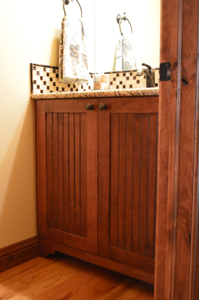 Photo of a small country powder room in Denver with recessed-panel cabinets and medium wood cabinets.
