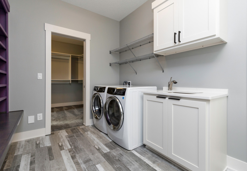 Photo of a large modern single-wall utility room in Other with an undermount sink, shaker cabinets, white cabinets, quartzite benchtops, grey walls, vinyl floors, a side-by-side washer and dryer, multi-coloured floor and white benchtop.