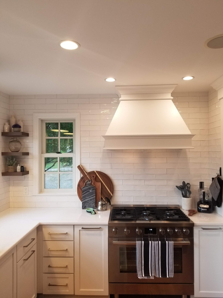 Photo of a large country l-shaped eat-in kitchen in New York with a farmhouse sink, shaker cabinets, white cabinets, marble benchtops, yellow splashback, ceramic splashback, stainless steel appliances, medium hardwood floors, with island, brown floor, white benchtop and exposed beam.