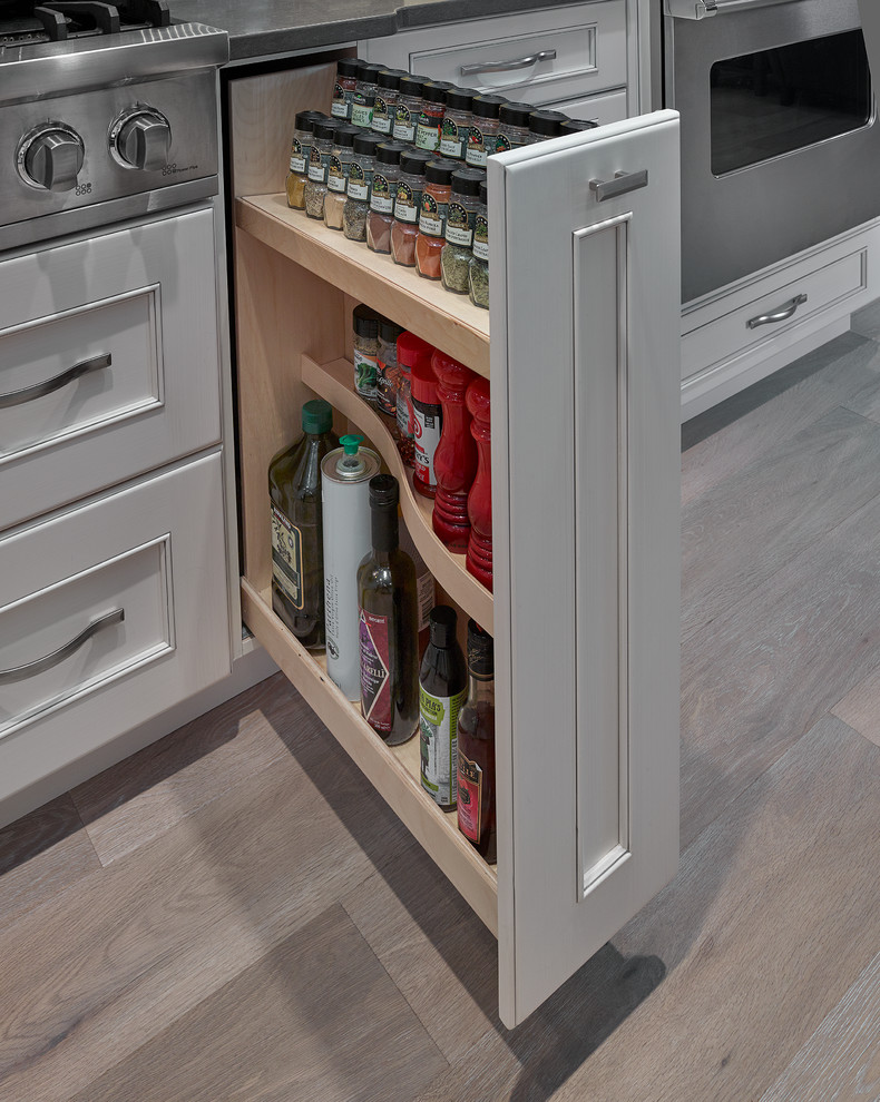 Inspiration for a large transitional l-shaped light wood floor and beige floor eat-in kitchen remodel in Edmonton with a farmhouse sink, recessed-panel cabinets, white cabinets, quartz countertops, stainless steel appliances, an island, gray backsplash and matchstick tile backsplash
