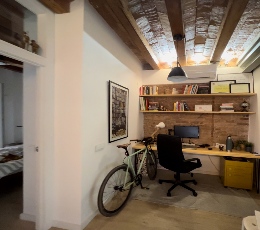 Kleines Mediterranes Arbeitszimmer mit weißer Wandfarbe, hellem Holzboden, braunem Boden, freigelegten Dachbalken und Ziegelwänden in Barcelona