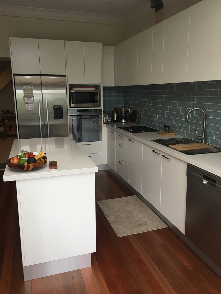 Inspiration for a contemporary kitchen pantry in Sydney with a double-bowl sink, white cabinets, grey splashback, subway tile splashback, stainless steel appliances, medium hardwood floors and with island.
