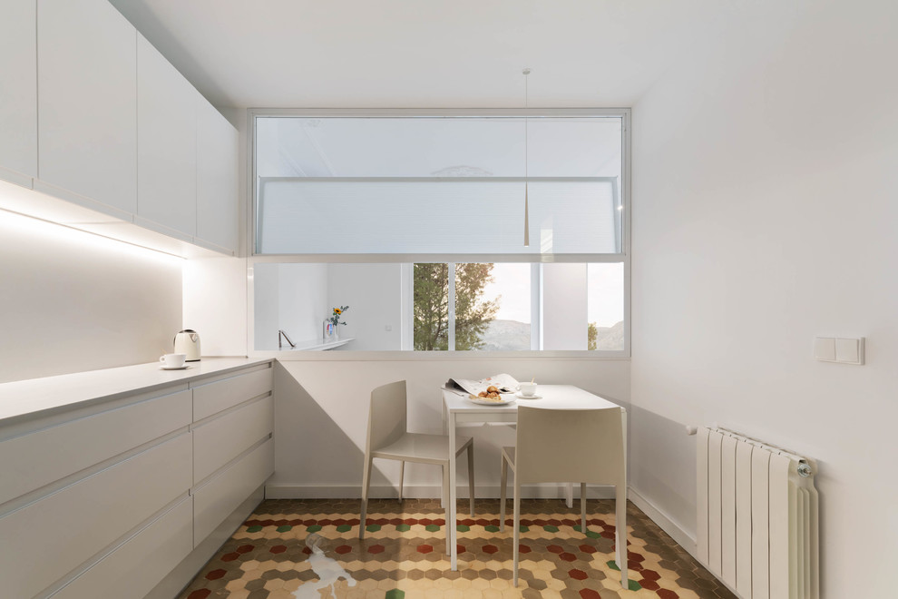 Design ideas for a large transitional l-shaped eat-in kitchen in Valencia with an undermount sink, flat-panel cabinets, light wood cabinets, quartz benchtops, beige splashback, limestone splashback, white appliances, cement tiles, no island, multi-coloured floor and beige benchtop.